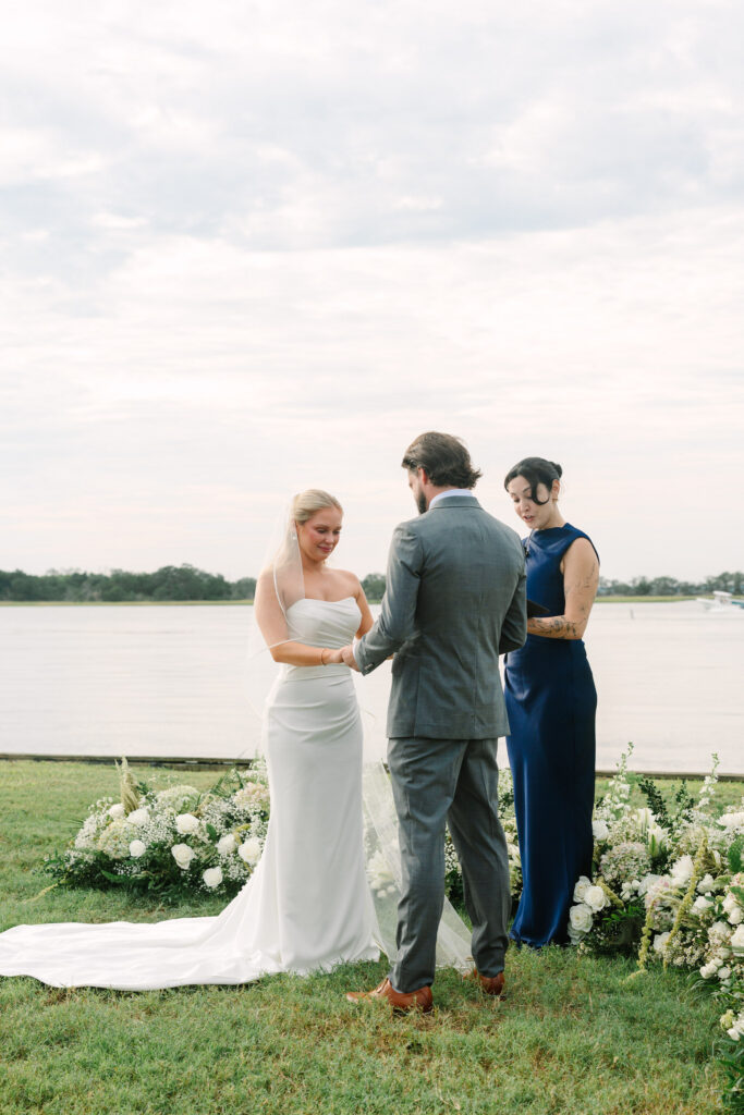 Bride and groom exchanging rings during a waterfront wedding ceremony at The Island House on Johns Island