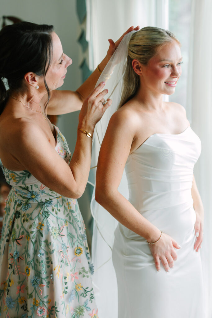 Bridesmaid adjusting the bride's veil before her wedding ceremony at The Island House